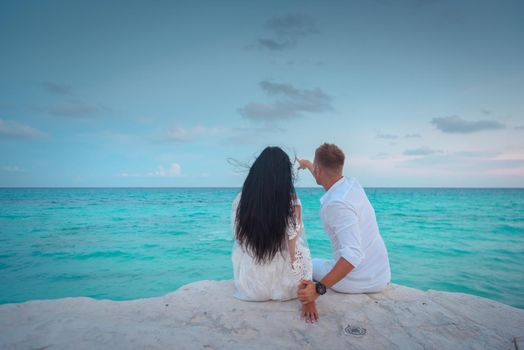 A man and a woman are sitting on the seashore.