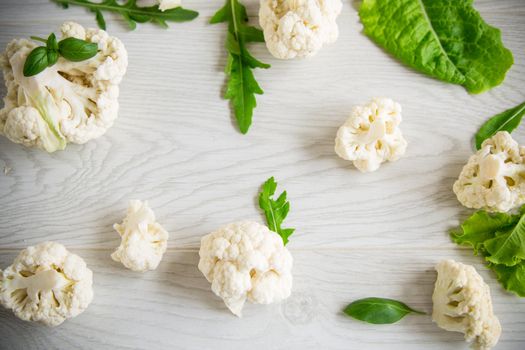 inflorescences of small raw cauliflower on a light wooden table