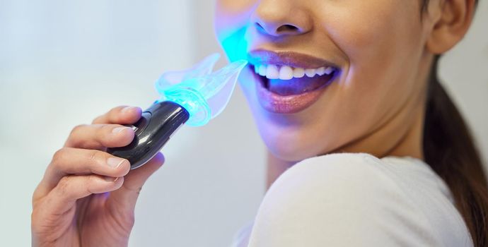 an unrecognisable woman having her teeth whitened at the dentist.