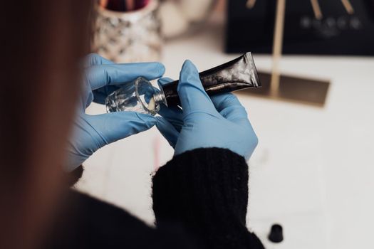 Close Up of Make-Up Artist in Gloves Squeezes a Tube of Paste Into Vessel