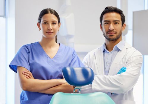 Portrait of a young dentist and his assistant working in their consulting room.