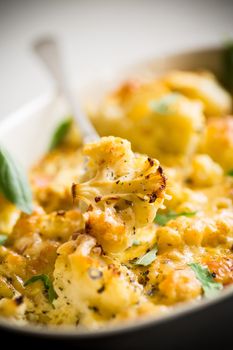 baked cauliflower with vegetables and cheese and scrambled eggs in a ceramic dish
