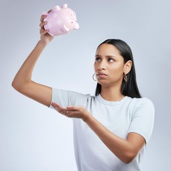 a woman holding an empty piggy bank.