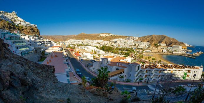 February 2 2022-Panoramic landscape with Puerto Rico village resort and beach on Gran Canaria Spain with yellow sand and volcanic mountains on the background
