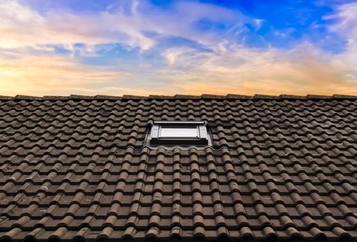 Roof window in velux style with dark roof tiles