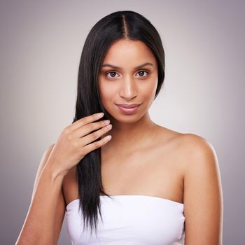 an attractive young woman holding her hair while posing in the studio.