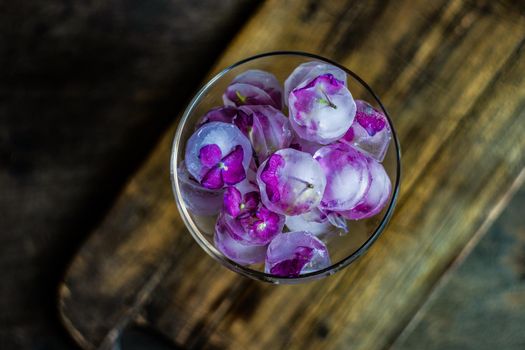 Glass with purple hydrangea flower ice cubes as a refreshing summer drink concept