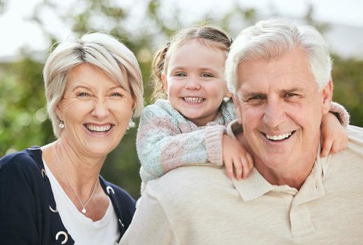 a senior couple spending time outdoors with their granddaughter.