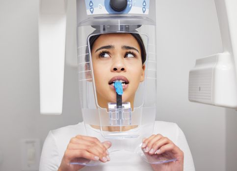 a young woman looking anxious while using an x ray machine at a dentists office.