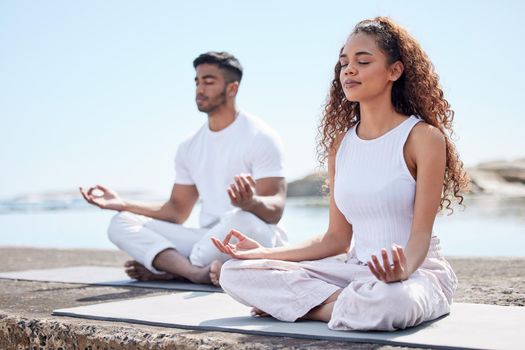 Full length shot of a young couple practicing yoga at the beach.