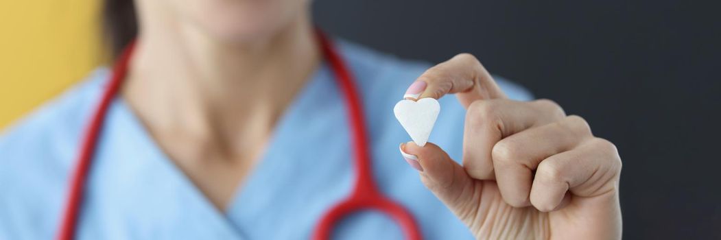 Close-up of female medical worker show small white heart on camera. Save life through donation or charity. Medicine, cardiology, healthcare, help concept