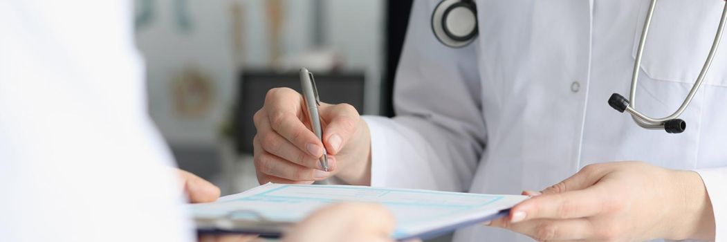 Close-up of doctor in medical gown put sign on clipboard with prescription paper. Qualified worker made prescription for patient. Medicine, clinic concept