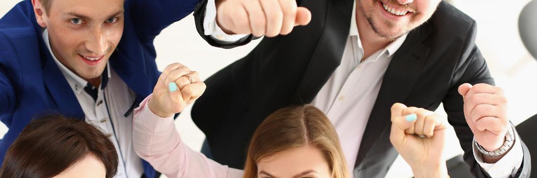 Top view of group of people show support gesture collectively in office. Well dressed workers posing with smile, cheerful mood. Business, teamwork concept