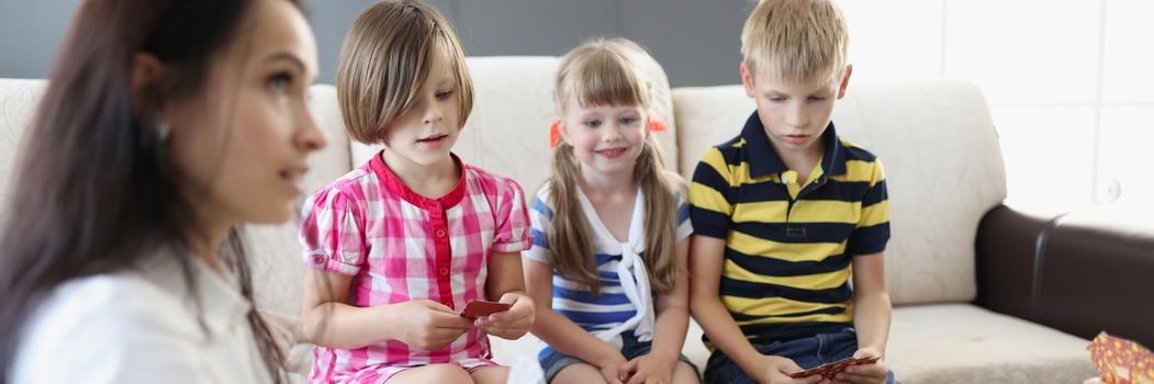 Portrait of group of kids spending time in kindergarten with female teacher. Woman entertain children with games and active pastime. Childhood, fun concept