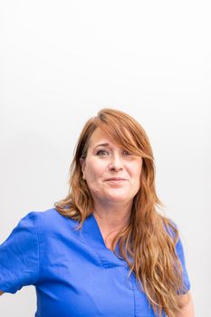 Portrait of a white dentist woman posing and smiling with joy for the camera after a day of work at the dental clinic hall