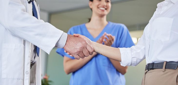 two unrecognizable people shaking hands at a hospital.