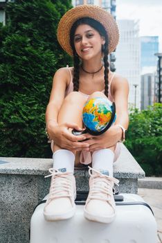 A beautiful young woman holds a small globe in her hands. Lifestyle and travel Concept