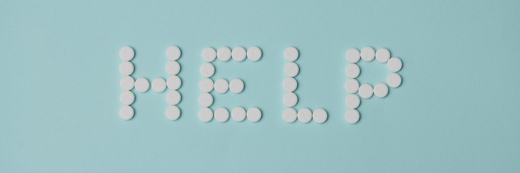 Top view of help lettering made with white round shaped pill, drug prescription for treatment. Pharmaceutical medicament, medicine, emergency, help concept