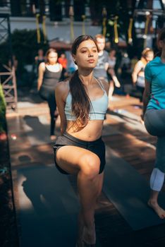 A woman does yoga together with her group in the open air. Healthy lifestyle concept