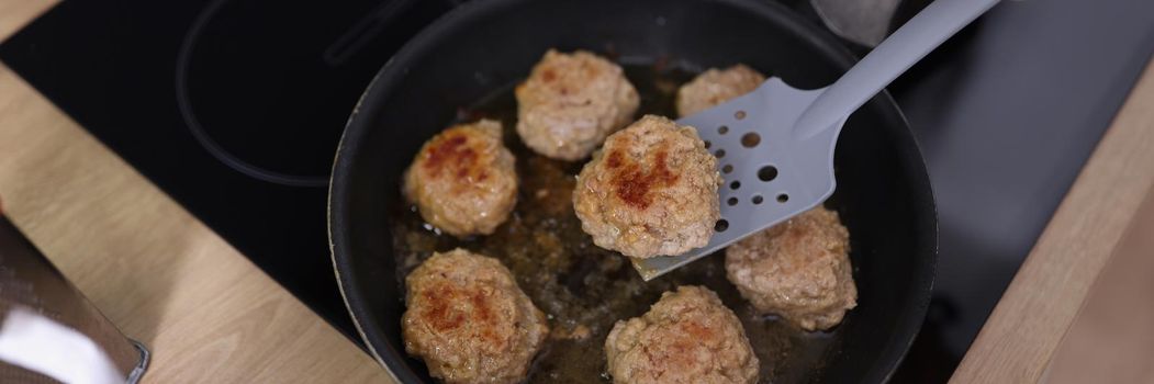 Top view of meat balls beginning to fry in oil in frying pan on kitchen stove. Housewife cooking fresh meal using tool. Chef, food, eating, dish concept