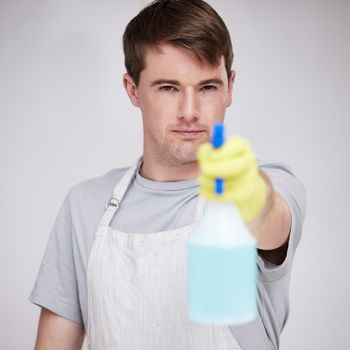 a young man holding a spray bottle against a grey background.