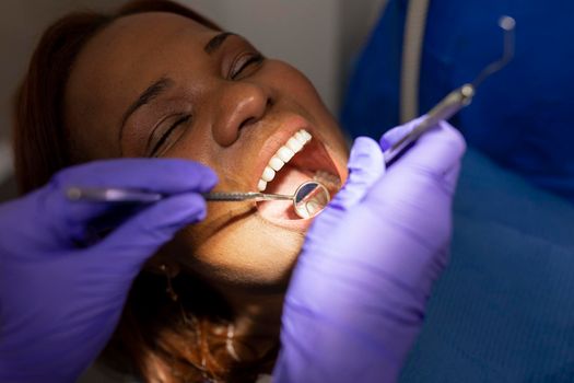 A dentist woman's hands using dental tools to treat the patient's oral issues while seated on the dental chair at the dental clinic