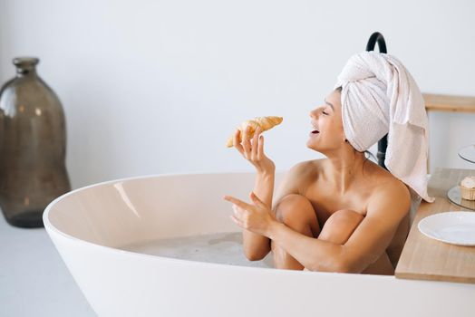 Fashion woman in the morning lying in the bath having breakfast