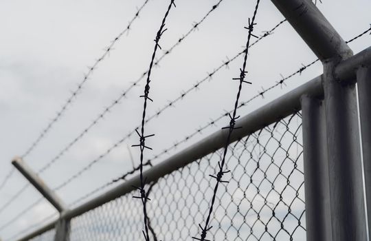 Prison security fence. Border fence. Barbed wire security fence. Razor wire jail fence. Boundary security wall. Prison for arrest of criminals or terrorists. Private area. Military zone concept. 