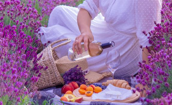 a girl in a lavender field pours wine into a glass. Relaxation. selective focus