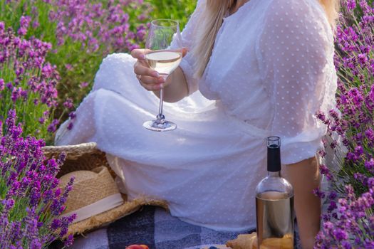 a girl in a lavender field pours wine into a glass. Relaxation. selective focus