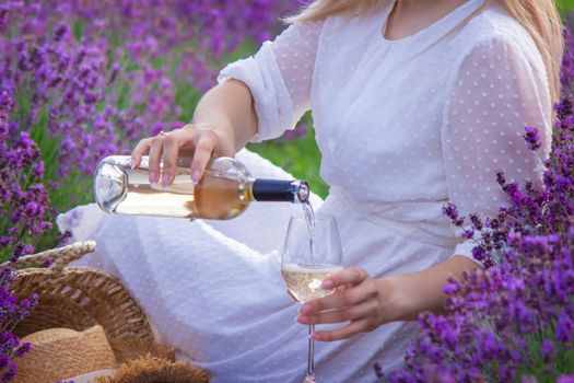a girl in a lavender field pours wine into a glass. Relaxation. selective focus