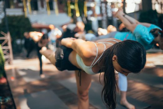 A woman does yoga together with her group in the open air. Healthy lifestyle concept