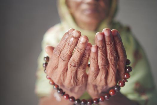 Close up of senior women hand praying at ramadan .