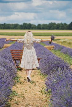 Young woman in a lavender field holding a bouquet of lavender a sunny day.