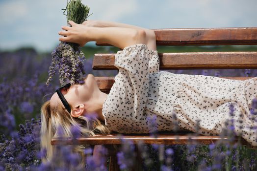 Relaxed young woman lies in a lavender field a sunny day.