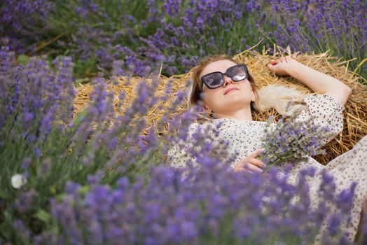 Relaxed young woman lies in a lavender field a sunny day.