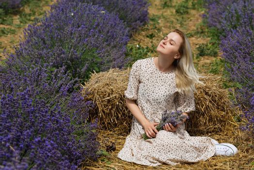 Relaxed young woman sitting in a lavender field a sunny day.