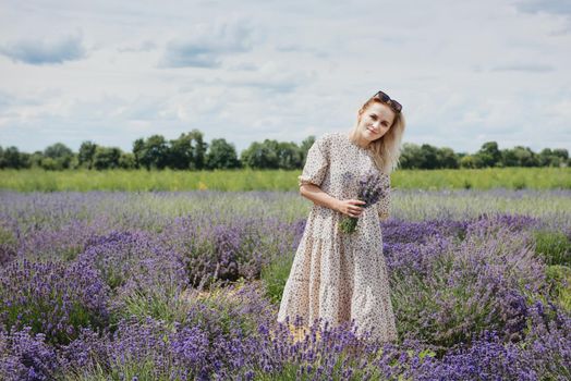 Young woman in a lavender field holding a bouquet of lavender a sunny day.