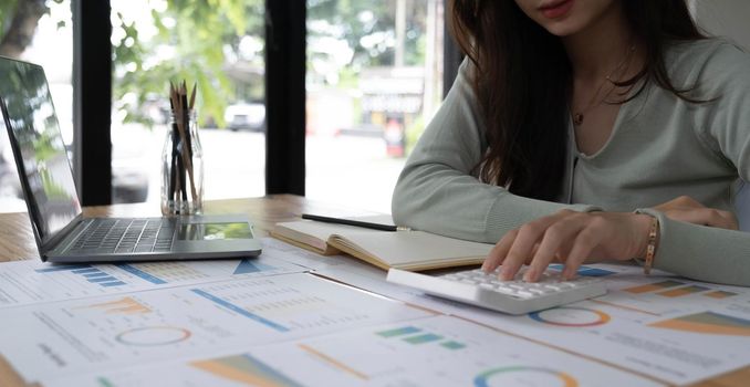 Portrait of asian business woman paying bills online with laptop in office. Beautiful girl with computer and chequebook, happy paying bills. Startup business financial calculate account concept.