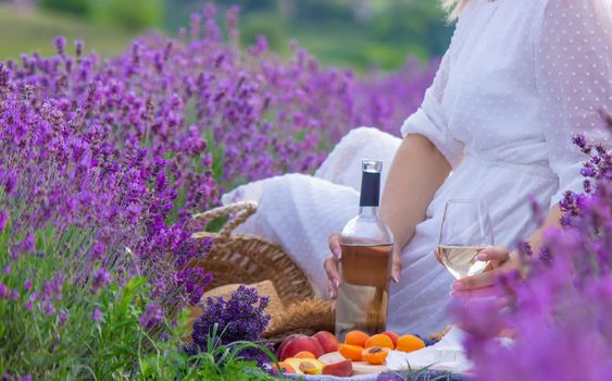 a girl in a lavender field pours wine into a glass. Relaxation. selective focus