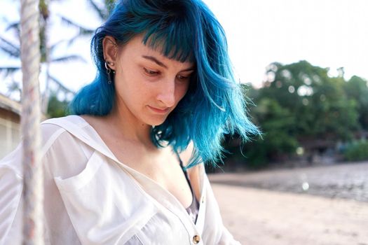 Relaxed alternative woman with blue hair looking down in a tropical beach