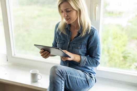 Young woman holding the tablet and sitting at home
