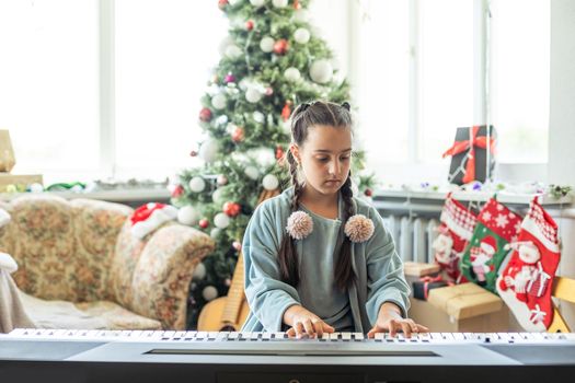 Christmas child little girl playing on piano at home.