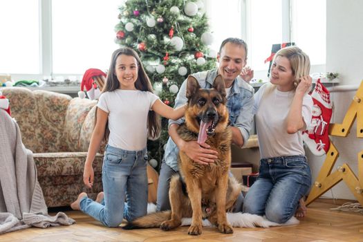 happy family and cute dog having fun at christmas tree. atmospheric emotional moments. merry christmas and happy new year concept