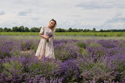 Young woman in a lavender field holding a bouquet of lavender a sunny day.