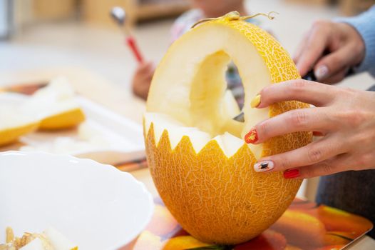Female hands cutting pumpkin to halloween in kindergarten