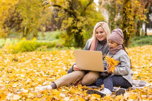Online communication. Family using laptop and video calling , sitting on picnic blanket in garden