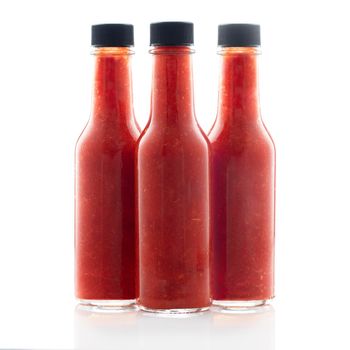 Three bottles of hot sauce without lables isolated on a white background.