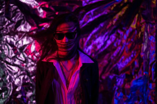 Portrait of a transgender model in sunglasses in a studio with neon lighting