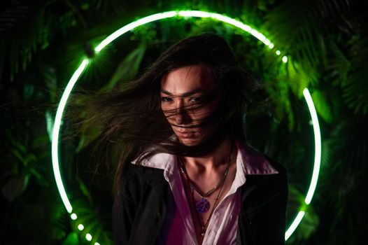 Portrait of an Asian man against the background of a circular lamp in the studio with neon light